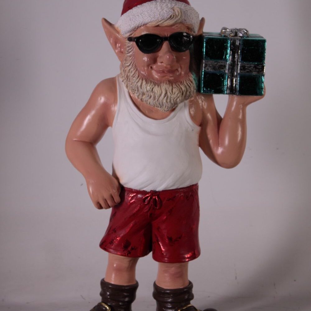 Christmas elf statue wearing Santa hat, sunglasses, red shorts, and holding a gift box.