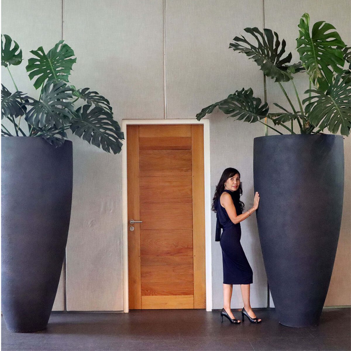 Natureworks Australia Flora Grande Planter - 6ft - 230121Matt Black- shown at entrance to office with lady
