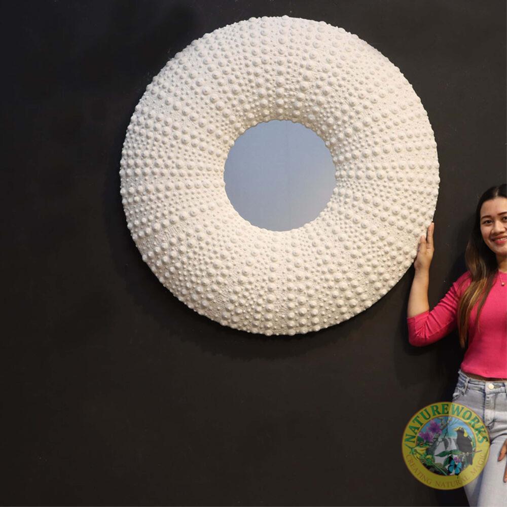 Sea urchin Mirror - 240014 finished with a whitestone textured urching details. - round shape - 110cm x 12cm x 110cm - seaside themed wall decor- shown with lady to help with size