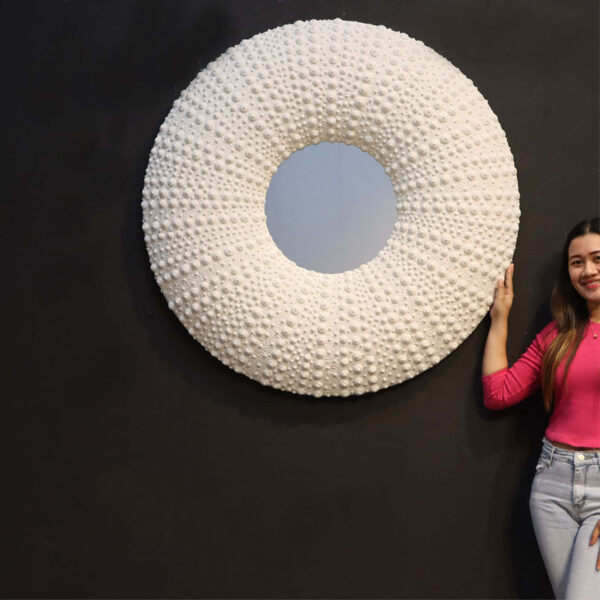 Sea urchin Mirror - 240014 finished with a whitestone textured urching details. - round shape - 110cm x 12cm x 110cm - seaside themed wall decor- shown with lady to help with size