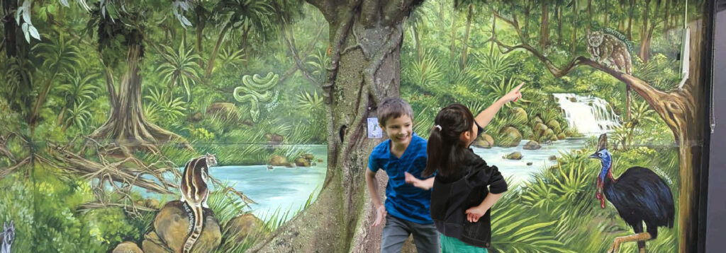 Children in front of Artificial fig tree and mural at William timson school