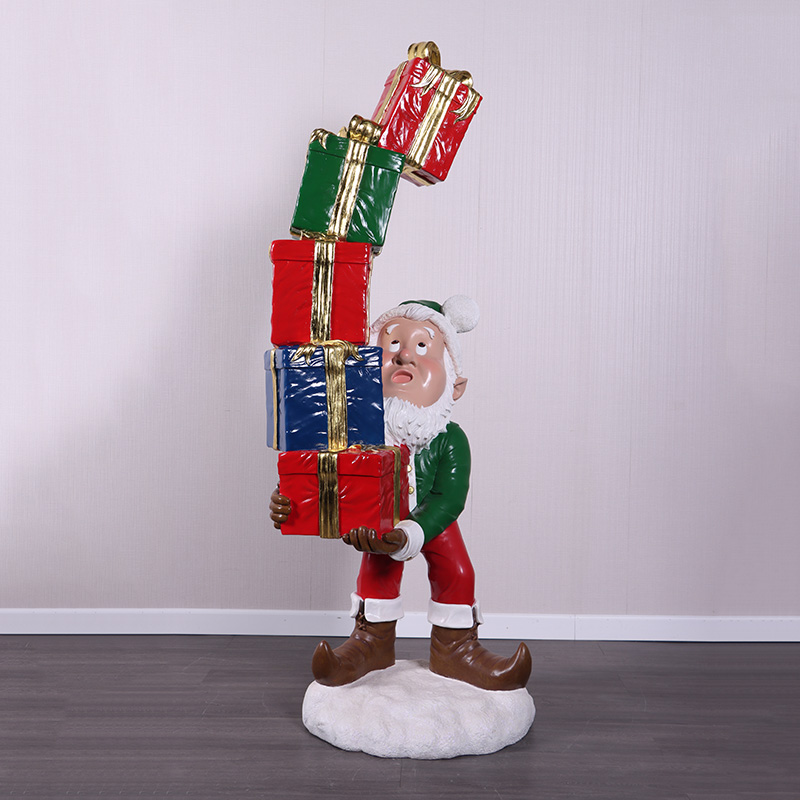 Christmas Elf with Stack of Gifts statue balancing colourful presents on a snow base