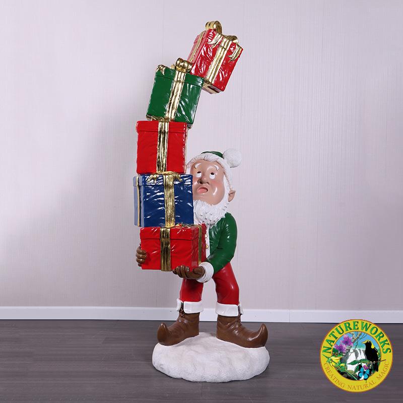 Christmas Elf with Stack of Gifts statue balancing colourful presents on a snow base