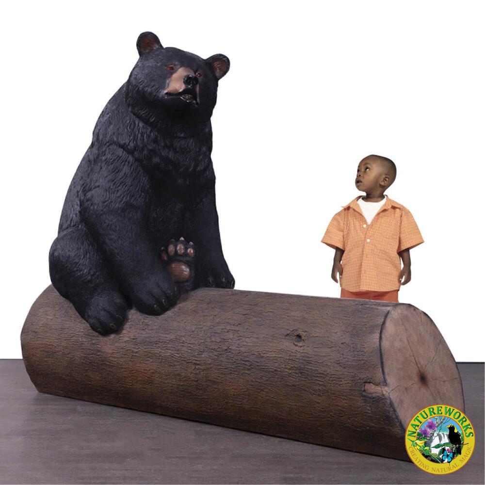 Bear sitting on tree trunk - bench seat - shown with boy - 240130