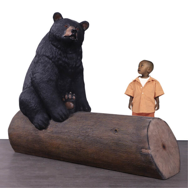 Bear sitting on tree trunk - bench seat - shown with boy - 240130