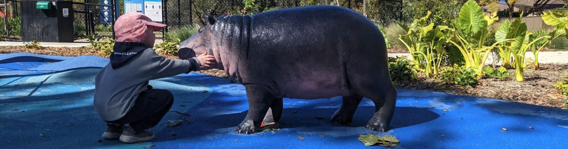 Safari-themed playground with hippo sculpture and child